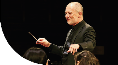 Conductor holding up a baton, leading violinists onstage.