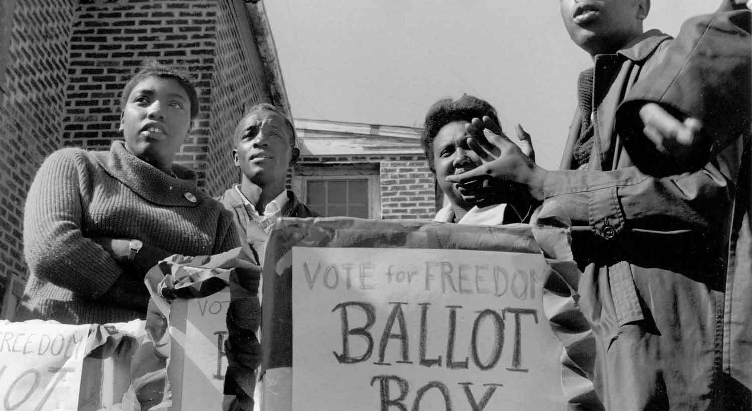 A photograph of SNCC organizers at a polling station in Greenwood, MA for a mock election, October 1, 1963. Ida Mae Holland is farthest left. (Photo: Matt Herron, Take Stock)